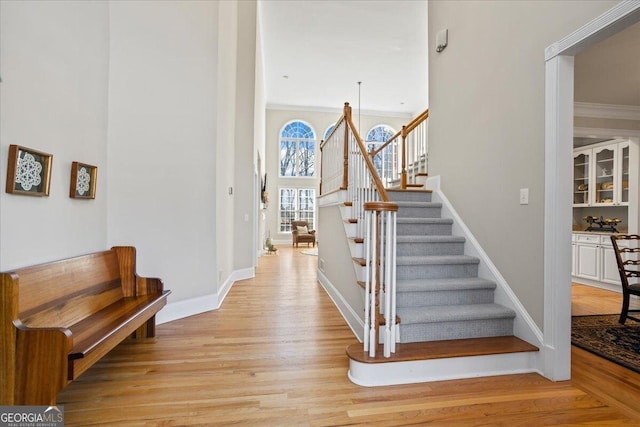 stairway with baseboards, wood finished floors, and crown molding