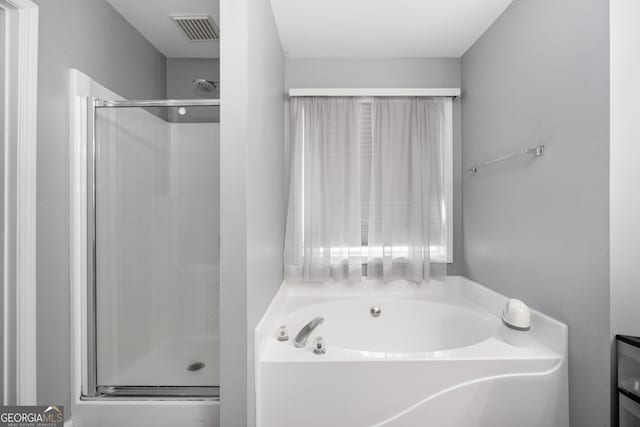 bathroom featuring visible vents, a garden tub, and a shower stall