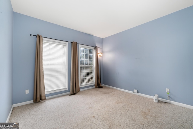 spare room with light carpet and baseboards