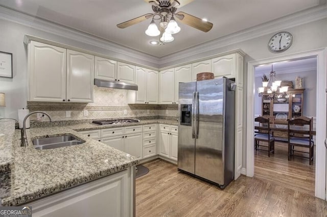 kitchen with light stone counters, light wood finished floors, stainless steel appliances, a sink, and under cabinet range hood