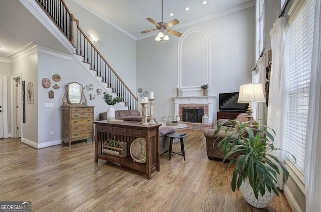living room featuring crown molding, a high ceiling, a fireplace, and wood finished floors