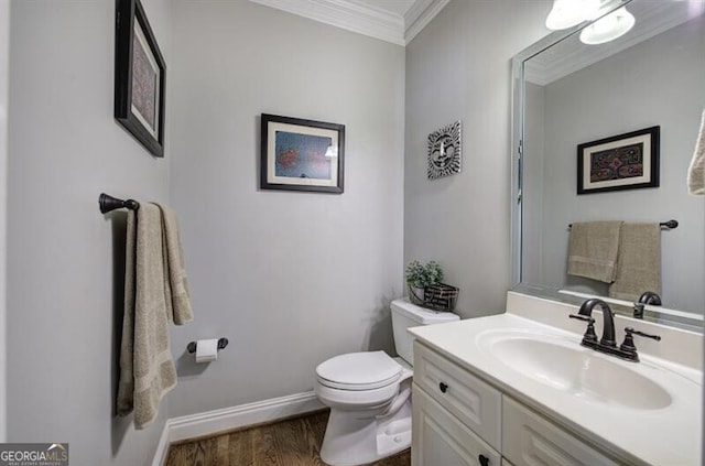 half bathroom featuring toilet, wood finished floors, vanity, baseboards, and ornamental molding