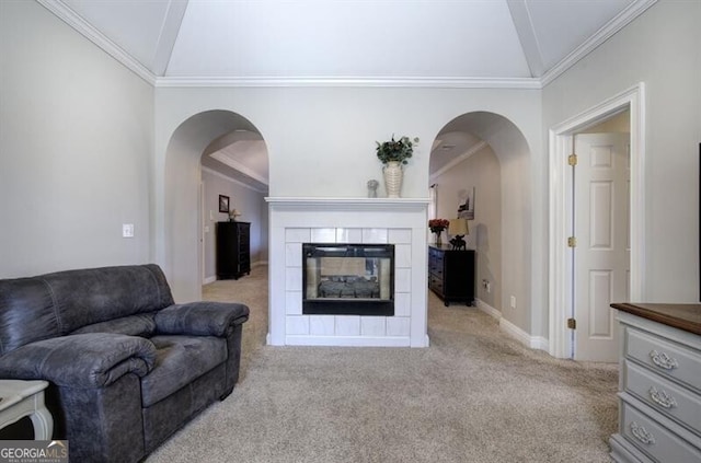 living area featuring carpet, crown molding, vaulted ceiling, and a tiled fireplace