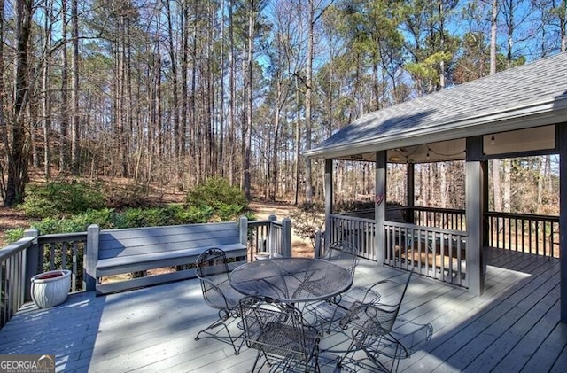 wooden terrace with outdoor dining area and a gazebo