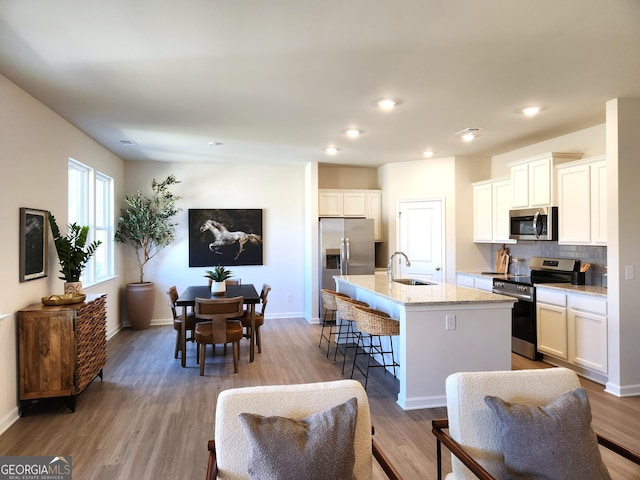 34 Russet Way Lot 57, Newnan, GA 30263 - kitchen with stainless steel appliances, a sink, a kitchen island with sink, a breakfast bar area, and wood finished floors