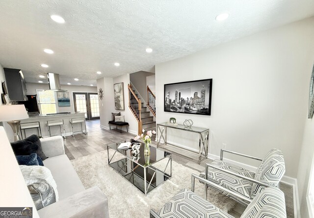 living area with a textured ceiling, baseboards, light wood-style flooring, and recessed lighting