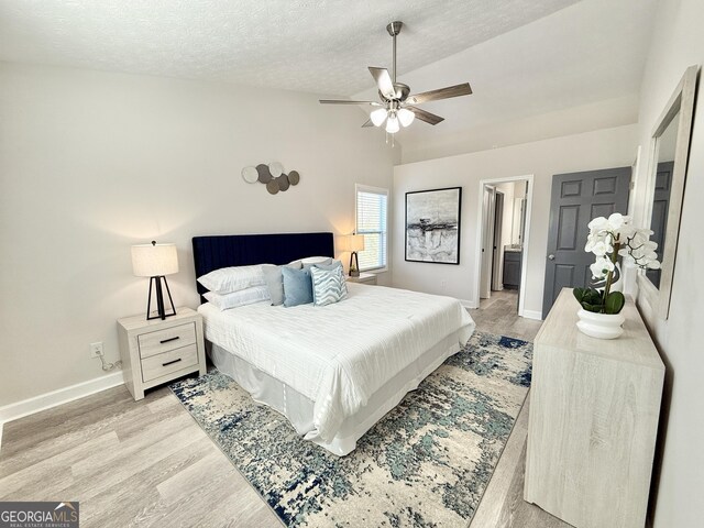 bedroom featuring lofted ceiling, light wood-style flooring, visible vents, and a textured ceiling