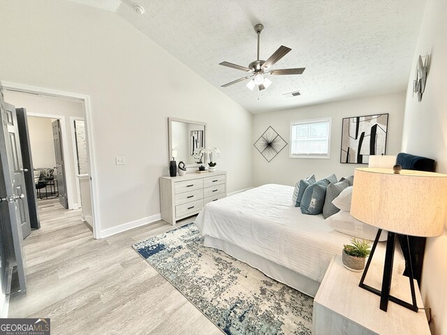 bedroom featuring baseboards, a ceiling fan, light wood-style flooring, vaulted ceiling, and a textured ceiling