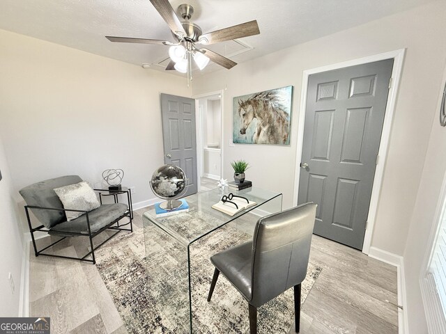 home office featuring visible vents, light wood-style flooring, ceiling fan, a textured ceiling, and baseboards