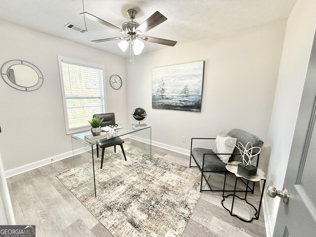 unfurnished room with visible vents, baseboards, a ceiling fan, light wood-style flooring, and a textured ceiling