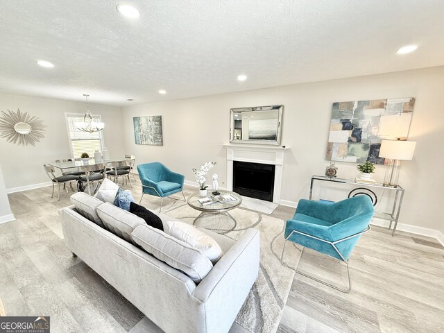 dining room with recessed lighting, an inviting chandelier, light wood-style floors, a textured ceiling, and baseboards