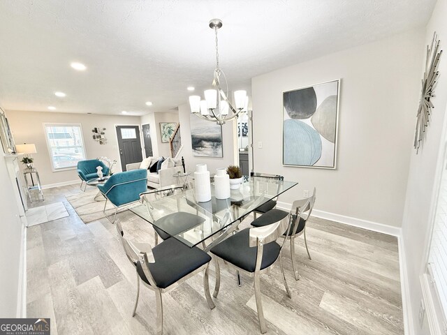 dining area featuring a fireplace, visible vents, light wood-style floors, a textured ceiling, and baseboards