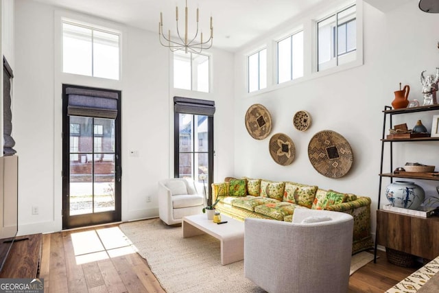 interior space with hardwood / wood-style flooring, a high ceiling, baseboards, and a chandelier