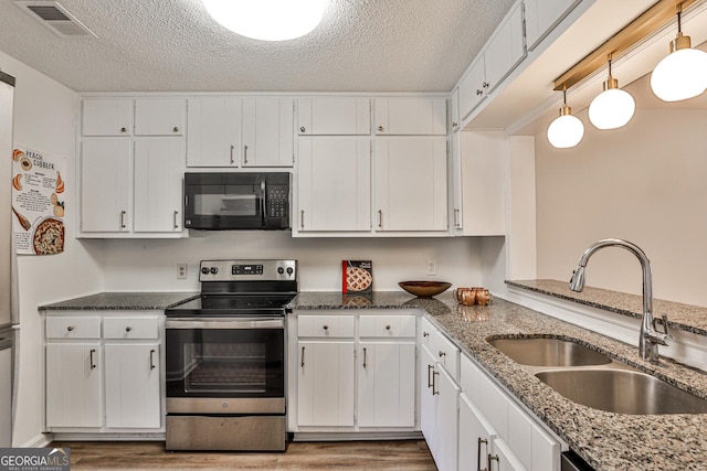 kitchen featuring black microwave, electric stove, decorative light fixtures, and white cabinets