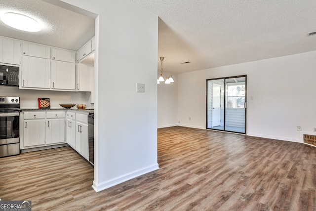 kitchen featuring dark countertops, open floor plan, white cabinets, light wood-type flooring, and black appliances