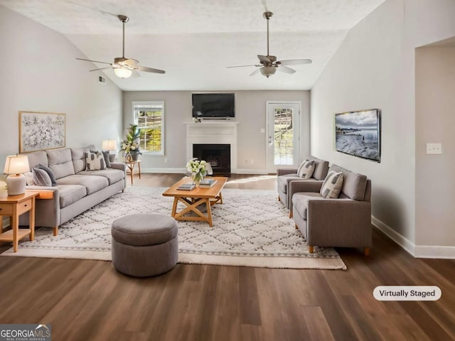 living area featuring vaulted ceiling, a fireplace, and wood finished floors