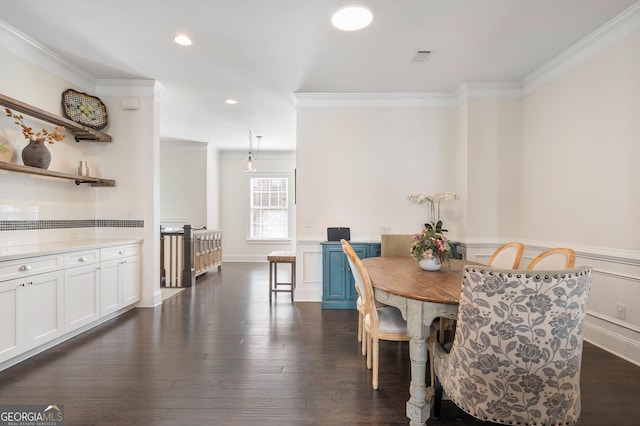 dining area featuring dark wood-style floors, ornamental molding, and wainscoting