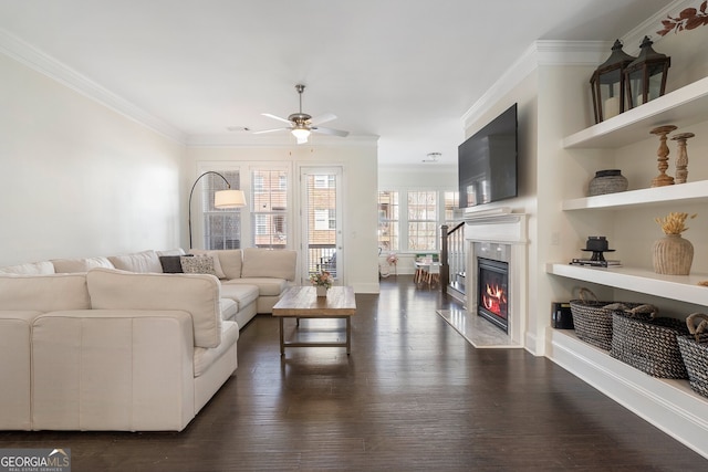 living area with ornamental molding, a fireplace, dark wood finished floors, and built in features