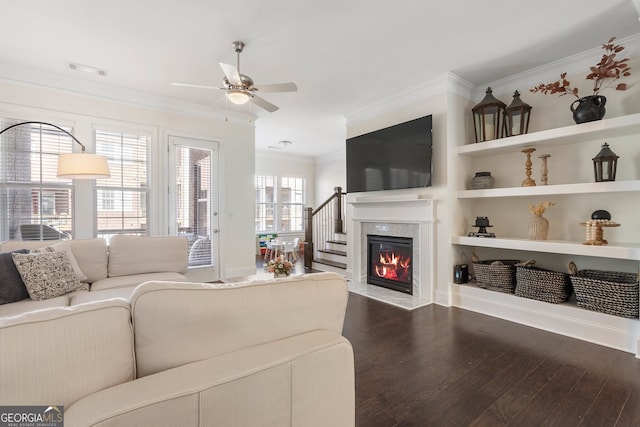 living area with built in shelves, a fireplace, dark wood finished floors, visible vents, and ornamental molding