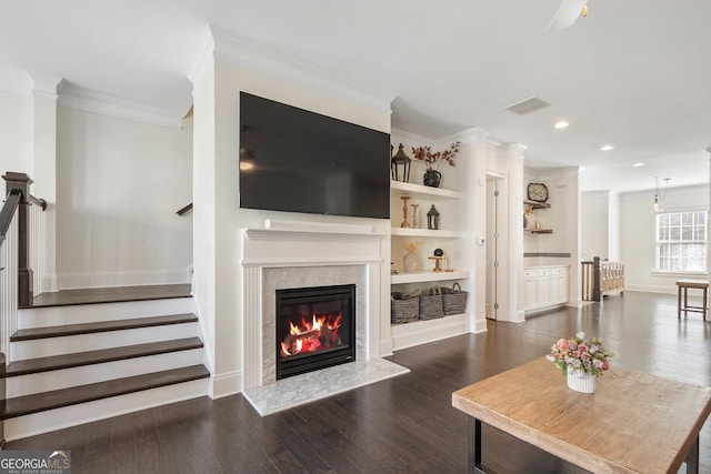 living room featuring visible vents, stairway, dark wood-style flooring, crown molding, and a fireplace