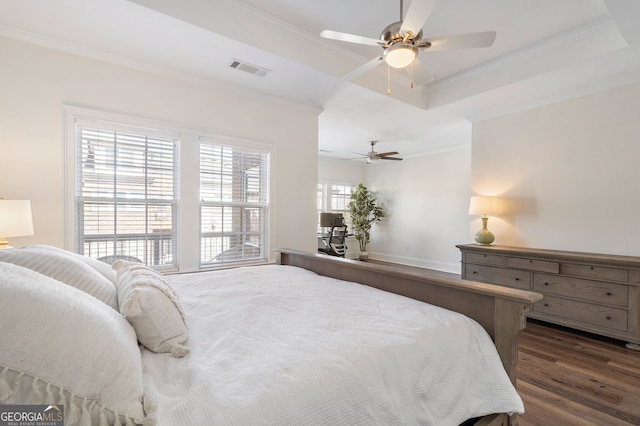 bedroom featuring a tray ceiling, dark wood finished floors, visible vents, ornamental molding, and a ceiling fan