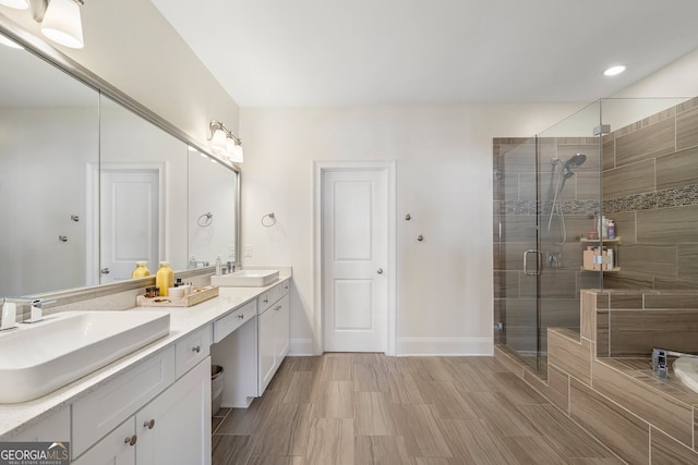 full bathroom with a sink, a shower stall, baseboards, and double vanity