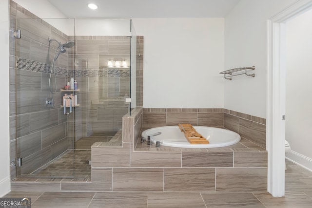 bathroom featuring a stall shower, a garden tub, and toilet