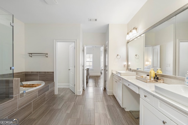 bathroom with a garden tub, a sink, visible vents, and double vanity