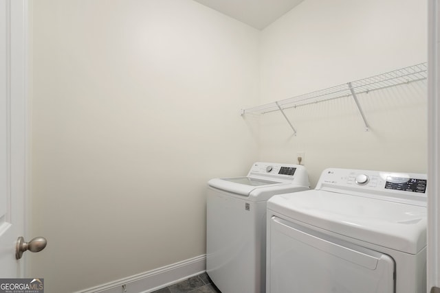 laundry area with laundry area, washing machine and dryer, and baseboards