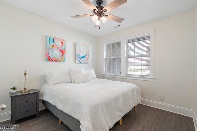 bedroom with baseboards, visible vents, dark wood finished floors, and a ceiling fan