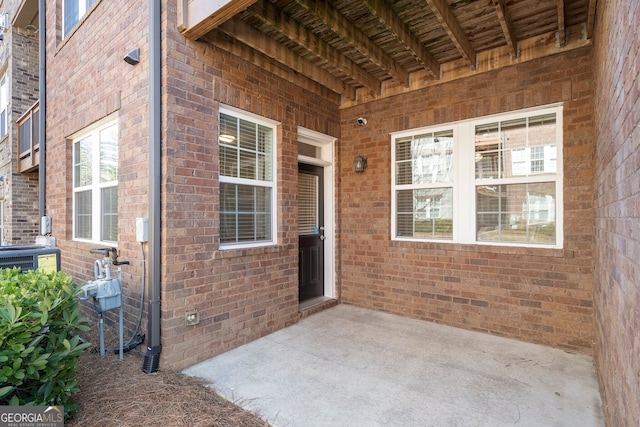 property entrance with a patio and brick siding