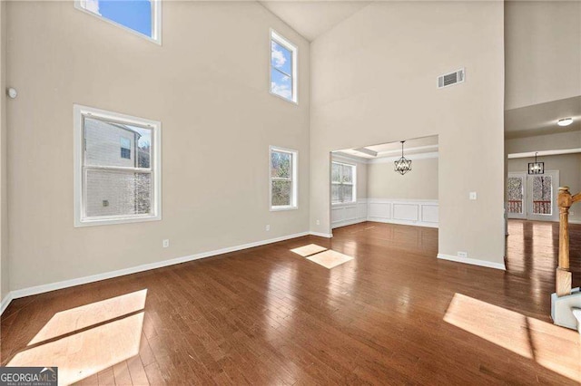 unfurnished living room with plenty of natural light, visible vents, and hardwood / wood-style floors