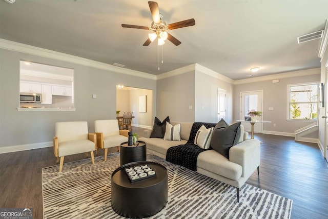 living area with dark wood-type flooring, visible vents, ornamental molding, and baseboards