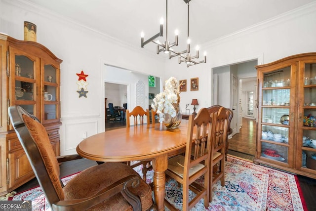 dining area featuring crown molding, a decorative wall, dark wood-type flooring, wainscoting, and a chandelier