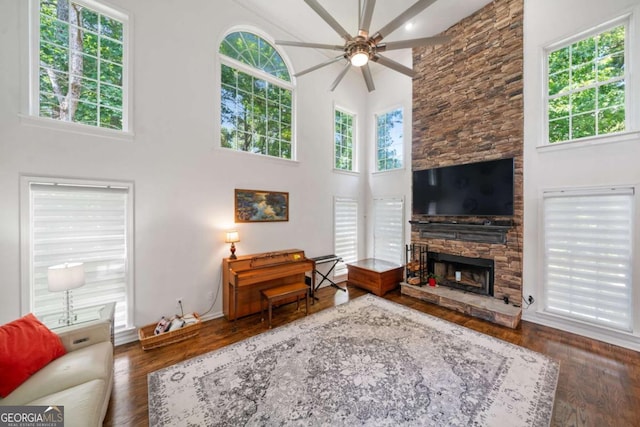 living area featuring dark wood-style floors, a fireplace, and a high ceiling