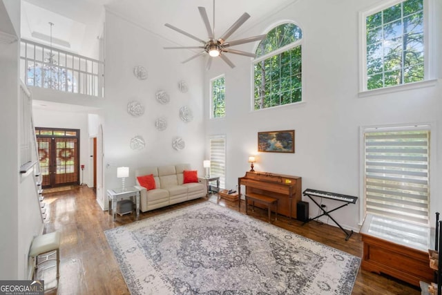 living room with a high ceiling, wood finished floors, and a ceiling fan