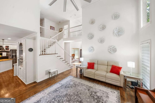 living area with visible vents, stairs, a high ceiling, and dark wood-style flooring