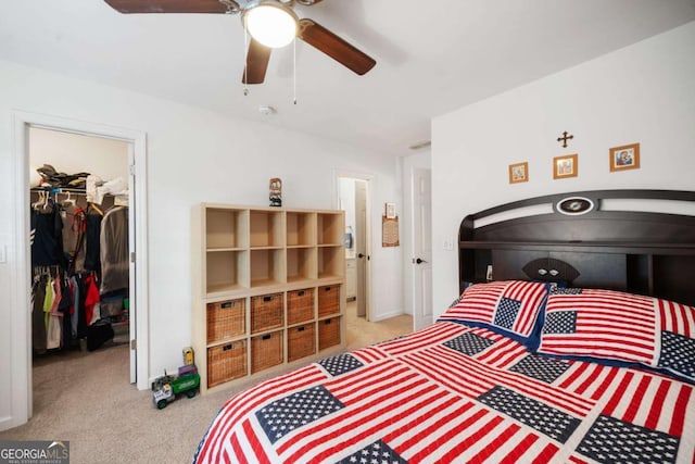 bedroom featuring light carpet, ceiling fan, a spacious closet, and a closet