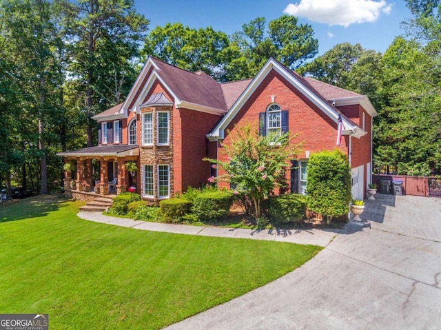 view of front of house featuring an attached garage, concrete driveway, brick siding, and a front yard