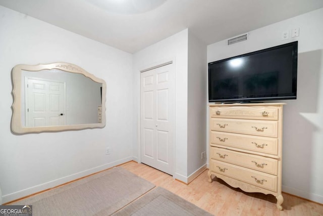 bedroom with a closet, wood finished floors, visible vents, and baseboards