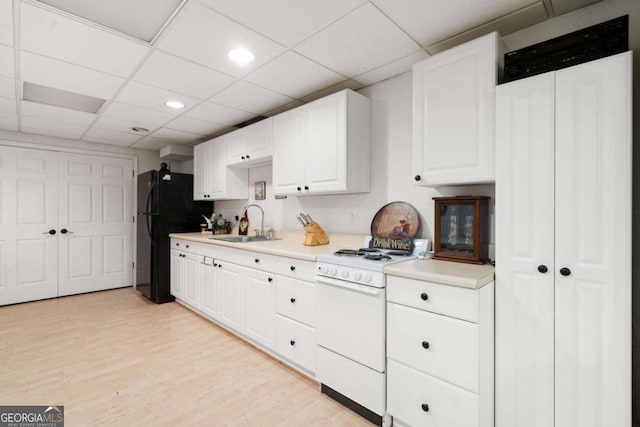 kitchen featuring white range with electric cooktop, light countertops, white cabinetry, a sink, and light wood-type flooring