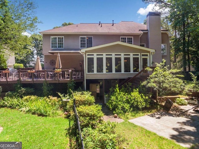 rear view of house with stairs, a chimney, a wooden deck, and a sunroom