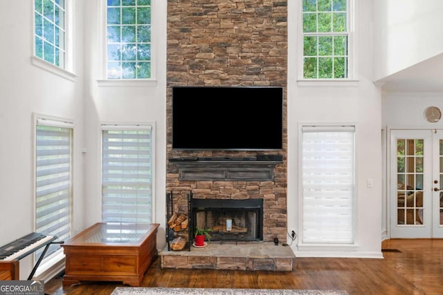 living area featuring a fireplace, a high ceiling, wood finished floors, and french doors