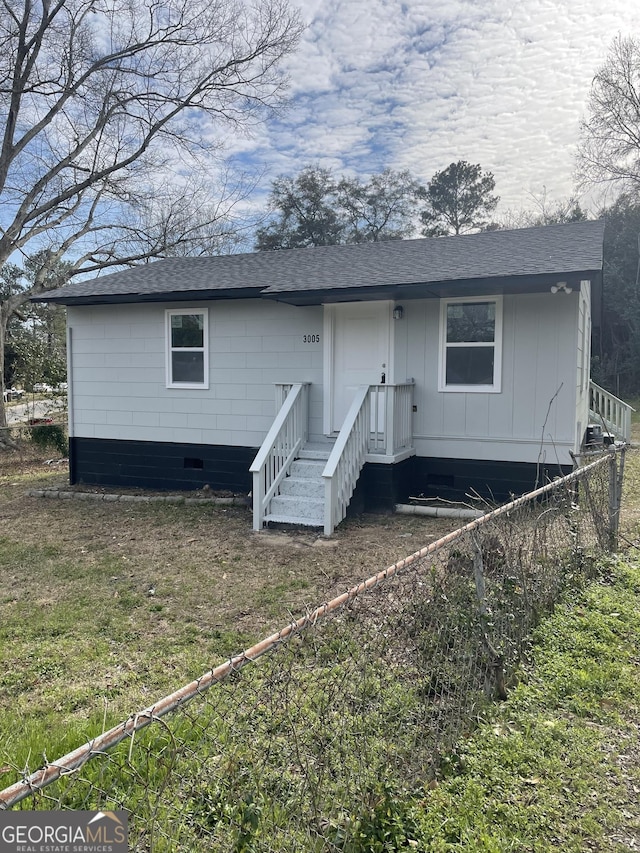 rear view of property with crawl space and a shingled roof