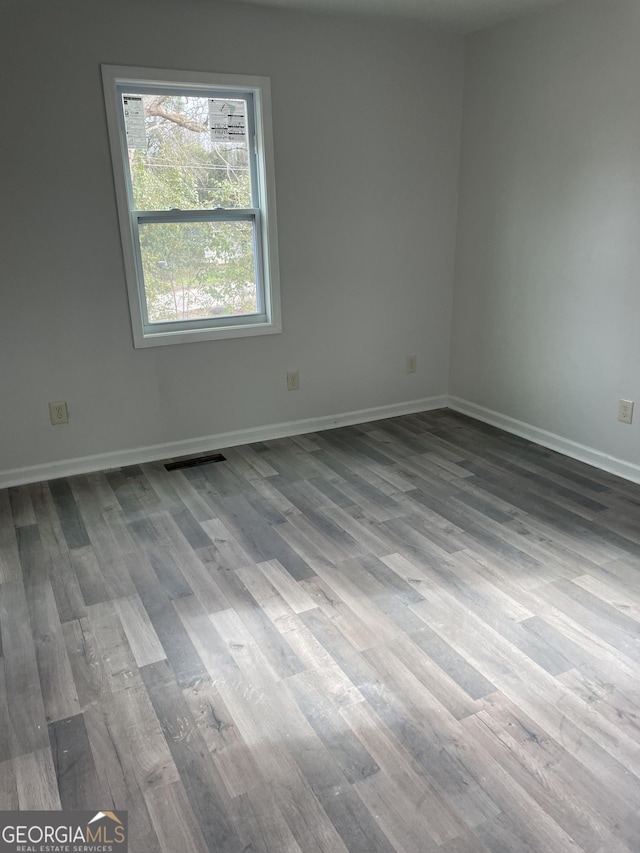 empty room featuring visible vents, baseboards, and wood finished floors