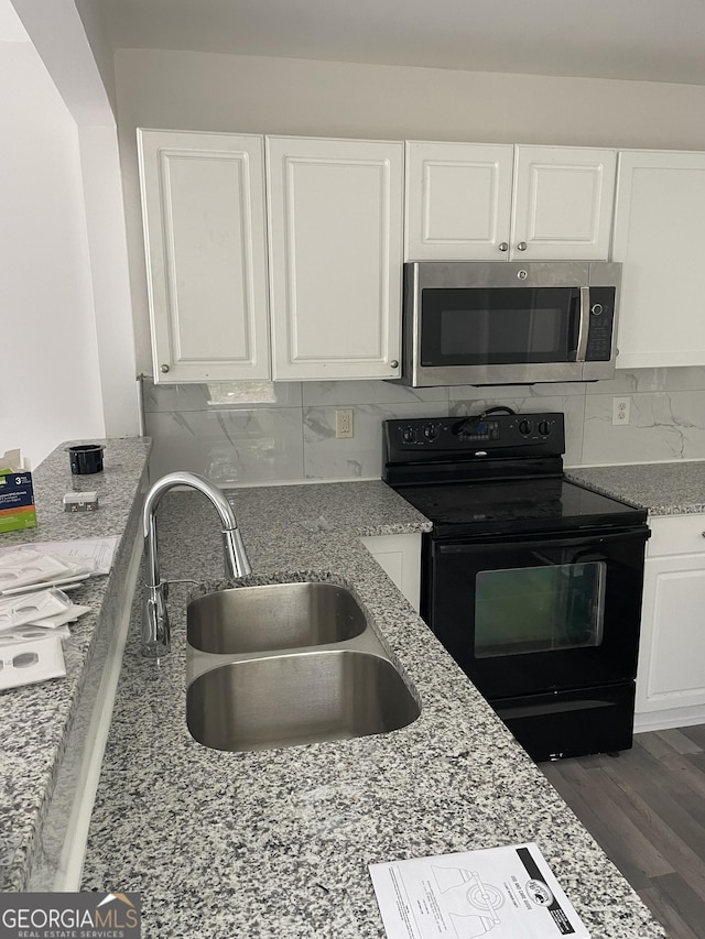 kitchen with a sink, white cabinetry, black electric range, tasteful backsplash, and stainless steel microwave