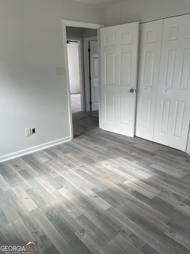 unfurnished bedroom featuring a closet, wood finished floors, and baseboards