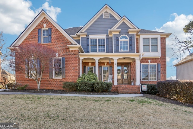 traditional home featuring covered porch, a front lawn, and brick siding