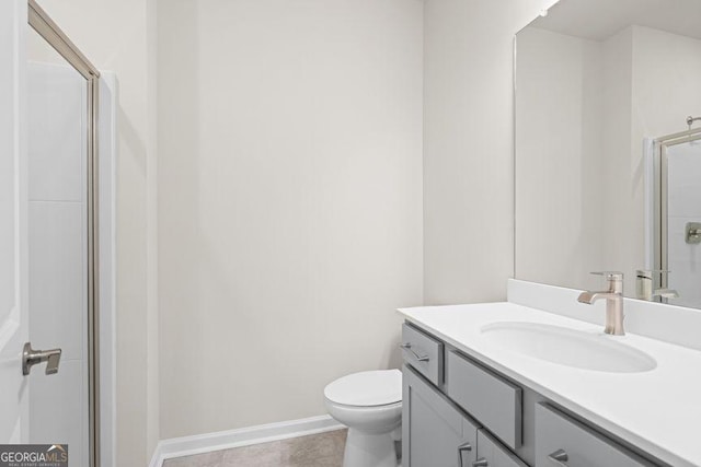 bathroom with toilet, vanity, baseboards, a shower stall, and tile patterned floors