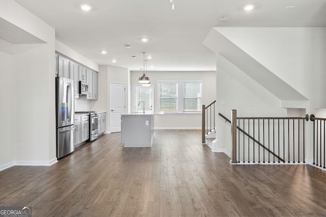 kitchen featuring dark wood-style floors, a center island, hanging light fixtures, stainless steel appliances, and light countertops